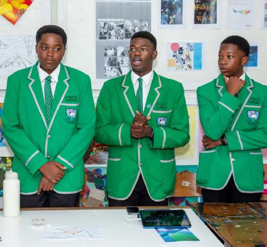 Three students in green blazers in a classroom